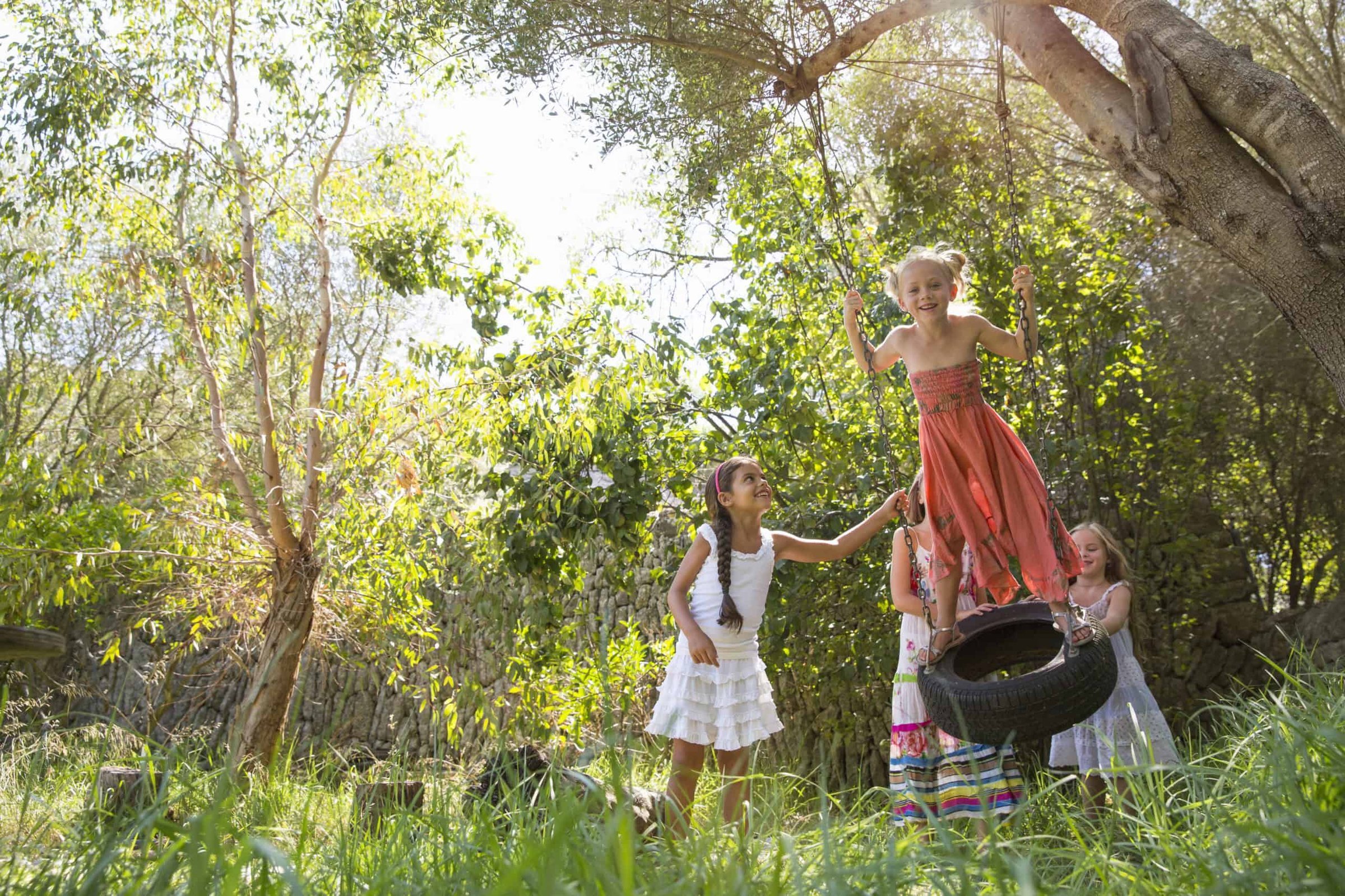 four-girls-playing-on-tree-tire-swing-in-garden-2024-11-03-05-39-35-utc-scaled